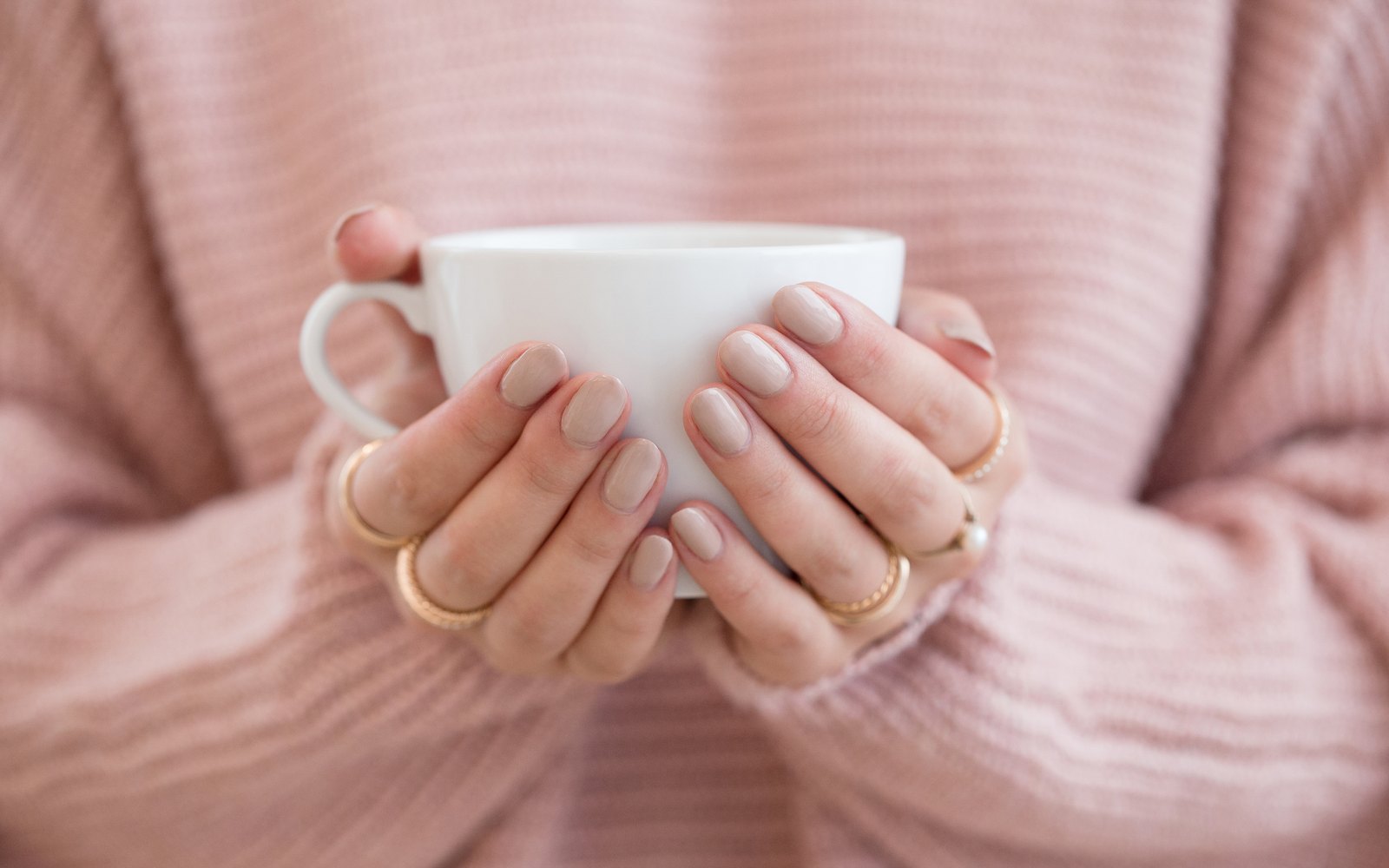 Frau hält eine Tasse mit beiden Händen, Symbolbild für Reizdarm und die Suche nach der Ursache
