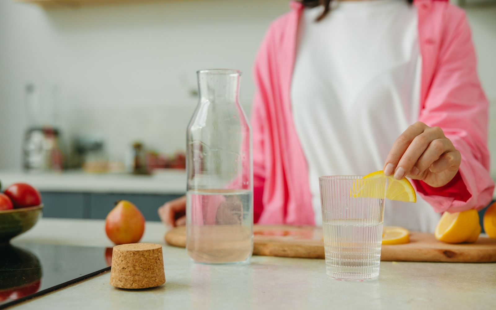Frau bereitet in einer hellen Küche ein Glas Wasser mit Zitrone zu, Symbolbild für die Vorbereitung auf den SIBO-Atemtest
