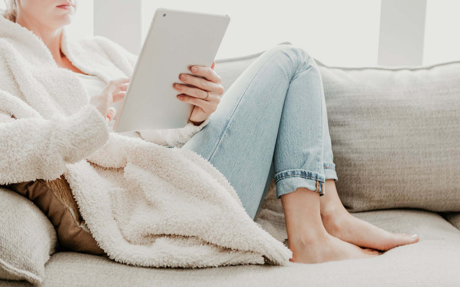 Frau informiert sich entspannt mit einem Tablet auf dem Sofa, Symbolbild für den SIBO-Atemtest