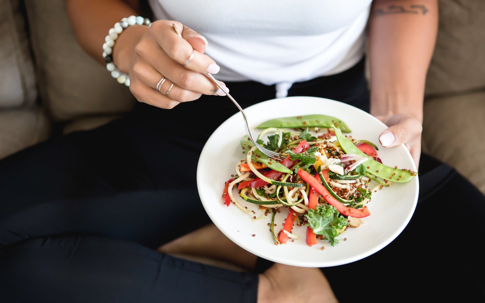 Frau isst einen frischen Gemüsesalat, Symbolbild für Blähbauch nach dem Essen